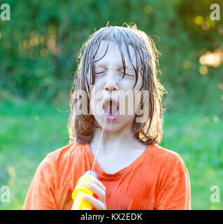 Wet Boy herum täuschen mit der Wasserpistole bespritzen. Stockfoto