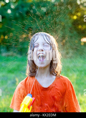 Wet Boy herum täuschen mit der Wasserpistole bespritzen. Stockfoto