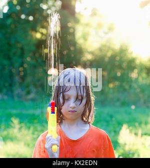 Wet Boy herum täuschen mit der Wasserpistole bespritzen. Stockfoto