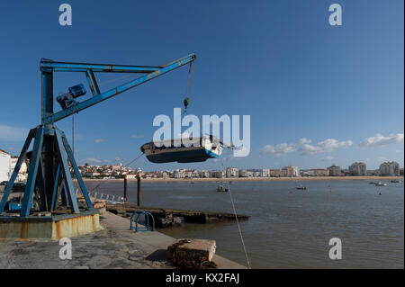 Kleines Fischerboot aus dem Hafen heraus Anheben mit dem Kran Flaschenzug wird in São Martinho do Porto, Portugal. Stockfoto