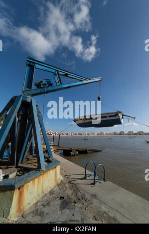 Kleines Fischerboot aus dem Hafen heraus Anheben mit dem Kran Flaschenzug wird in São Martinho do Porto, Portugal. Stockfoto