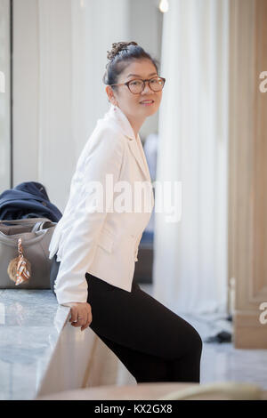 Schöne asiatische arbeitende Frau toothy Lächeln und Entspannend Stockfoto