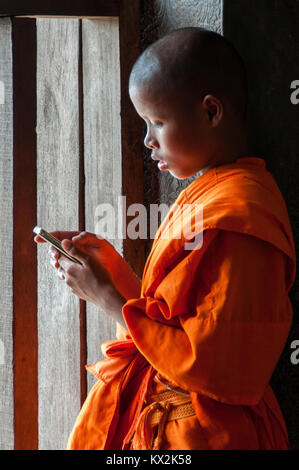 Junger buddhistischer Mönch mit Handy Stockfoto