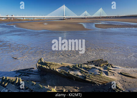 Gateway Bridge über den Fluss Mersey aus Widnes zu Runcorn gesehen mit ruinierten hölzernes Boot in den Schlamm. Stockfoto