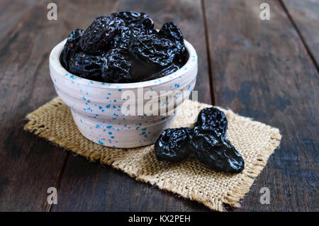 Pflaumen in einer Keramikschale auf einem dunklen Hintergrund. Getrocknete Früchte. Stockfoto