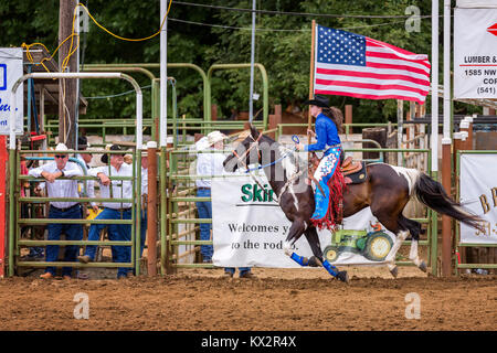 Cowgirl mit einer amerikanischen Flagge bei der Eröffnungsfeier eines Rodeo, Philomath Frolic & Rodeo, Oregon, USA Stockfoto