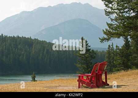 Zwei rote Stühle mit Blick auf Johnson Lake und die Berge im Banff National Park Stockfoto