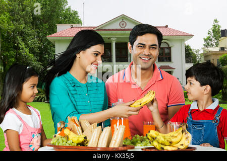 Glückliche Familie Frühstück Mutter geben Banane Sohn außerhalb Home Stockfoto