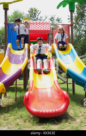 Indische Schule Kinder, Schüler, Freunde Folie Jhulla Spaß im Park Stockfoto