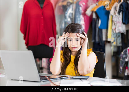 1 Weibliche Boutique Eigentümer Stuhl Kopfschmerzen Schmerzen in Clothe-Store Stockfoto