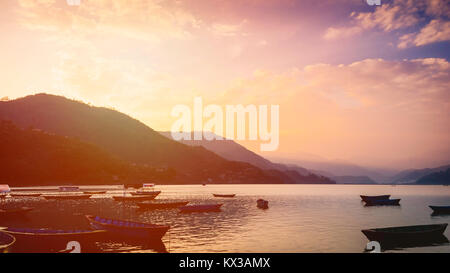 Sonnenuntergang über dem See mit Booten aus Holz in Pokhara Nepal gefüllt Stockfoto