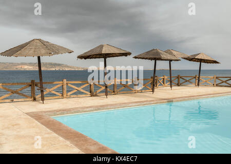 Ein Bild von einer Linie der Sonnenschirm Sonnenschirme mit einem Swimmingpool Schuß in Bugibba, St. Paul's Bay, Malta. Stockfoto