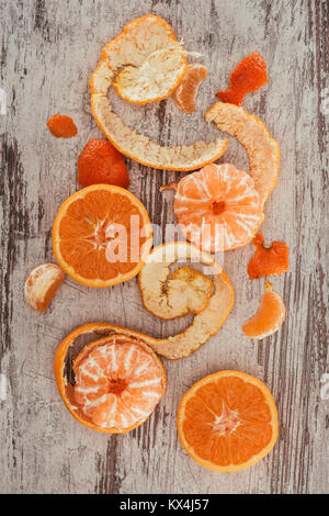 Ansicht von oben angeordnet, Mandarinen, Orangen Stückchen und Zitrone auf schäbige Holz- Oberfläche Stockfoto