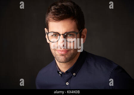 Nahaufnahme der ein hübscher junger Geschäftsmann auf dunklem Hintergrund. Stockfoto