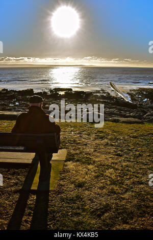 Ein älterer Mann auf einer Bank sitzen, das Meer bei Porthcawl, S. Wales Stockfoto