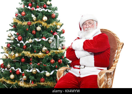 Weihnachtsmann im Schaukelstuhl mit verschränkten Armen sitzen und entspannen, Weihnachtsbaum, auf weißem Hintergrund eingerichtet Stockfoto