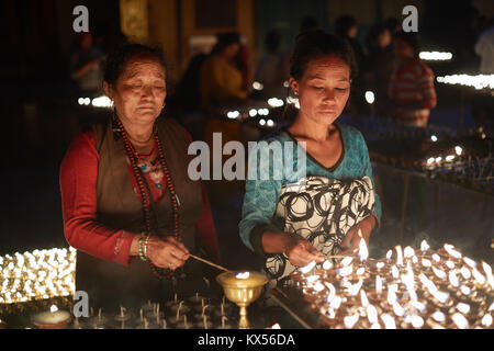 Tibetische Frauen Beleuchtung buddhistische Kerzen, Boudhanath, Kathmandu, Nepal Stockfoto