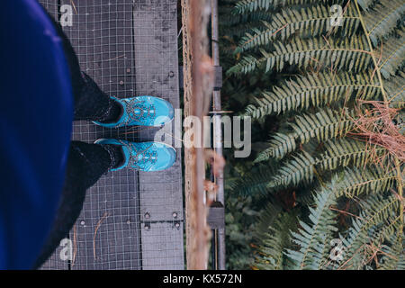 Weibliche in Wandern Outfit und Wanderschuhe steht auf einer Brücke im Dschungel in El Arenal Nationalpark, El Arenal Vulkan, La Fortuna, Alajuela, Costa Stockfoto