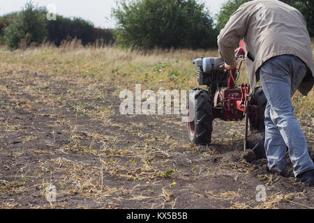 DIKANKA, UKRAINE - 30. SEPTEMBER 2015: Land Landwirt pflügt seinen Garten mit Garten hinter dem Traktor. Stockfoto