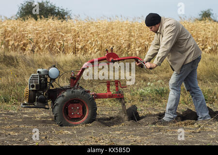 DIKANKA, UKRAINE - 30. SEPTEMBER 2015: Land Landwirt pflügt seinen Garten mit Garten hinter dem Traktor. Stockfoto