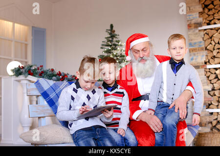 Kleine Jungen mit Santa Claus spielen mit Tablet. Stockfoto