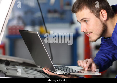 Seitenansicht Porträt eines mar Automechaniker Kontrolle der elektronischen Komponenten mit einem Laptop in einem Workshop Stockfoto