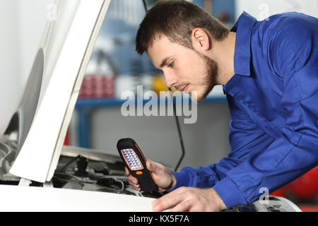 Seitenansicht eines Kfz-Mechaniker prüfen Motor für Defekte, die in einer mechanischen Werkstatt Stockfoto