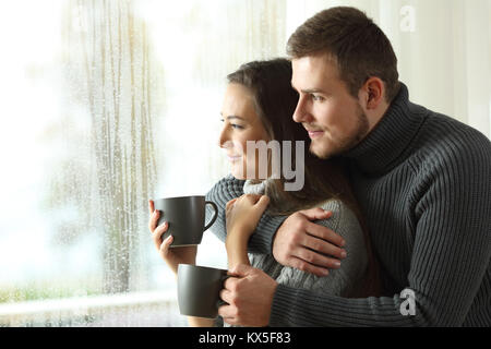 Portrait von ein glückliches Paar durch ein Fenster in einen regnerischen Tag der Winter Stockfoto