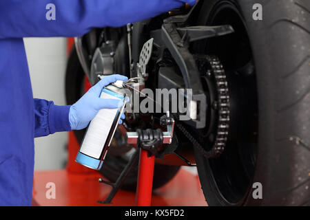 Nahaufnahme von einem Motorrad Mechaniker Hände aus Latex Handschuhe ölen ein Motorrad Kette in einem Workshop Stockfoto