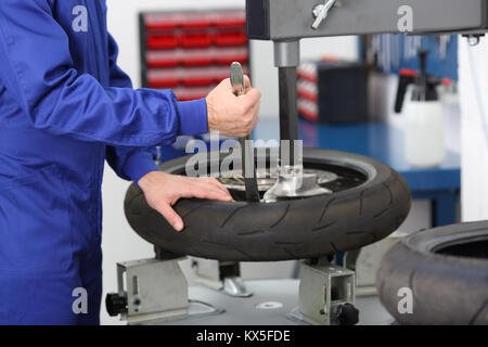 Motorrad Mechaniker Demontage eines alten Reifen in einer mechanischen Werkstatt Stockfoto