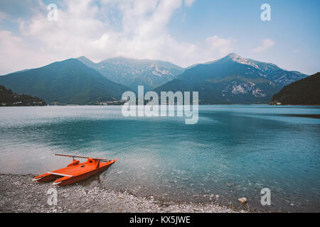 Italien Blick auf einen Bergsee Lago di Ledro mit Strand und ein rettungsboot Katamaran von roter Farbe im Sommer bei bewölktem Himmel. Stockfoto