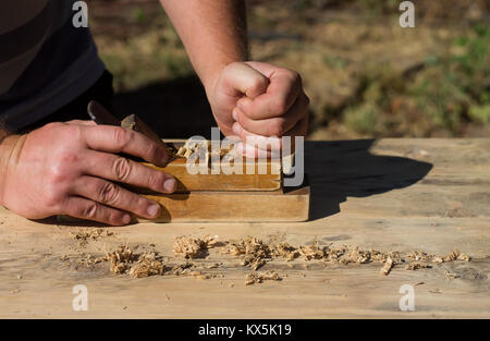 Die Hände eines Zimmermanns gehobeltes Holz Flugzeuge, die Arbeit an der Natur Stockfoto