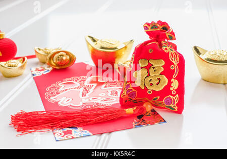 Chinesisches Neues Jahr, ang Pow rotem Filz Stofftasche mit gold Ingots und Orangen und Blumen auf weißem Holz Tischplatte, Chinesische Sprache bedeuten Glück und in Stockfoto