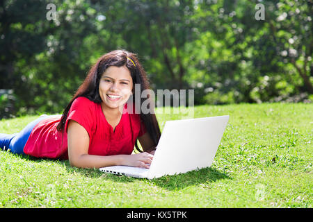 1 indischer Junge Frau Gras liegend mit Laptop genießen Park Stockfoto