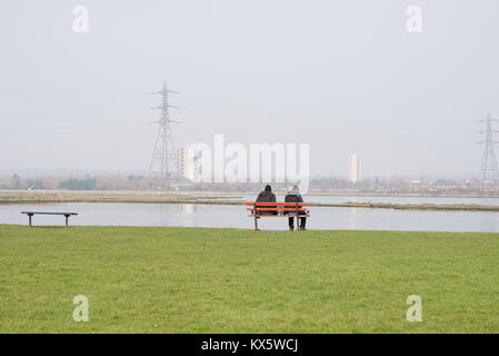 Zwei Personen sitzen auf einer Bank am Strommast und Hi suche - Rise Apartments Stockfoto