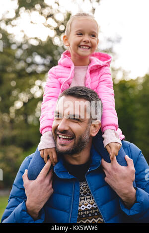 Süße kleine Mädchen reiten auf Vater zurück in den Park Stockfoto