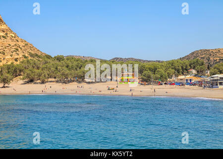 MATALA BAY, KRETA, GRIECHENLAND - 1. Mai: Menschen und Restaurants am Strand von Matala auf Kreta, Griechenland. Strand von Matala ist einer der schönsten Strände Stockfoto