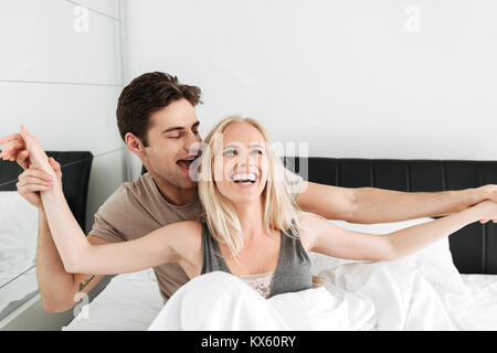 Heiter lustig Liebhaber, blond lächelnde Frau und Mann, umarmen im Bett und Lachen am Morgen Stockfoto