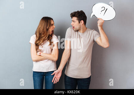 Portrait einer jungen stören Paar in ein Argument beim Stehen und die Sprechblase über graue Wand isoliert Stockfoto