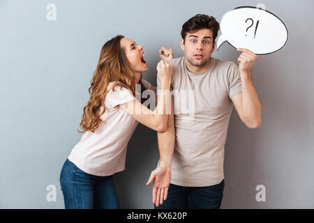 Portrait einer jungen mad Paar in ein Argument beim Stehen und die Sprechblase über graue Wand isoliert Stockfoto