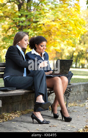 Zwei Unternehmerinnen Arbeiten am Laptop im Park Stockfoto