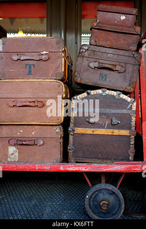 Schwarz und Braun Vintage Travel Koffer auf einem Trolley gestapelt. Stockfoto