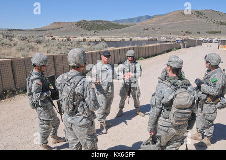 Sgt. 1. Klasse Erik Andersen (black hat), der als menschliche Intelligenz Sammler Beobachter/Controller während des Panther Streik 2012 serviert und ist an das Unternehmen B zugeordnet, 142 Military Intelligence Battalion, 300 MI Brigade, Kansas Army National Guard, dauert einen Moment außerhalb der Ausbildung Forward Operating Base auf Lager Williams, Arizona, zu den Soldaten der Task Force Panther 2 Bataillon über ihre Leistung auf einer Mission, die Sie gerade abgeschlossen hatte, 20. Juni sprechen. Panther Streik ist eine jährliche Übung des militärischen Geheimdienstes entwickelt gemeinsame Schulung und Bewertung der Aufklärung von t zur Verfügung zu stellen Stockfoto