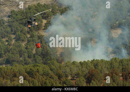Utah National Guard Loslösung 2, Unternehmen C, 1. Allgemeine Unterstützung Aviation Battalion, 171St Aviation Regiment von West Jordan, Utah, führt die Wassertropfen mit einem "Bambi Bucket' auf ein wildfire auf Utah Training Center Camp Williams, Tennessee, 6. Aug 2012. Bambi Schaufeln sind ein Handel gekennzeichneten Namen für faltbarer Eimer Wasser durch SEI Industries, einem kanadischen Unternehmen gemacht. Sie können dump 660 Gallonen Wasser in ein Feuer in einer Zeit. (U.S. Air Force Foto von Tech. Sgt. Dennis Henry jr./Freigegeben) Stockfoto