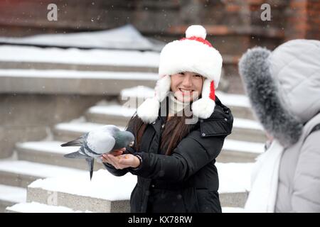 (180108) - HARBIN, Januar 8, 2018 (Xinhua) - ein Touristische füttert Tauben in ein Quadrat, Saint Sophia Kathedrale in Harbin, der Hauptstadt der Provinz Heilongjiang im Nordosten Chinas, Jan. 8, 2018. Die Stadt der erste Schnee in diesem Winter am Montag begrüßt. (Xinhua / Wang Kai) (zkr) Stockfoto