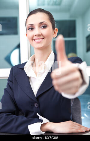 Attraktive junge geschäftsfrau hält ihre Hand in einen Daumen nach oben Geste Stockfoto