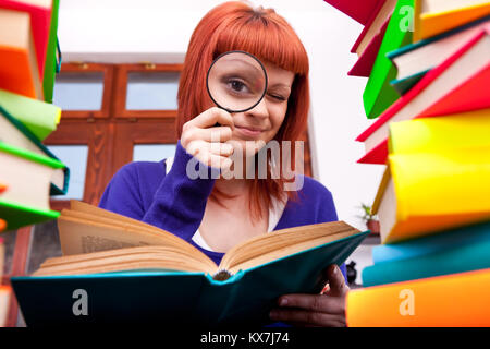 Lustig Teenager suchen etwas zwischen den Stapel Bücher Stockfoto