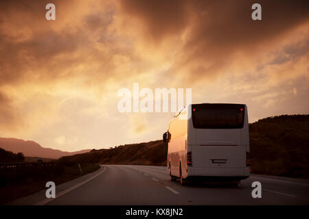 Weißen Bus fahren auf der Straße mit Blick auf den Sonnenuntergang Stockfoto