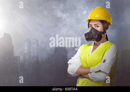 Schöne asiatische Frau Ingenieur mit Schutzmaske gegen Stadt Hintergrund Stockfoto