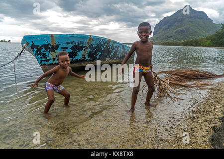 Spielende Kinder vor dem Berg Le Morne Brabant, Black River, Mauritius, Afrika | Kinder spielen am Strand, auf der Halbinsel Le Morne, Black River, Mauritiu Stockfoto